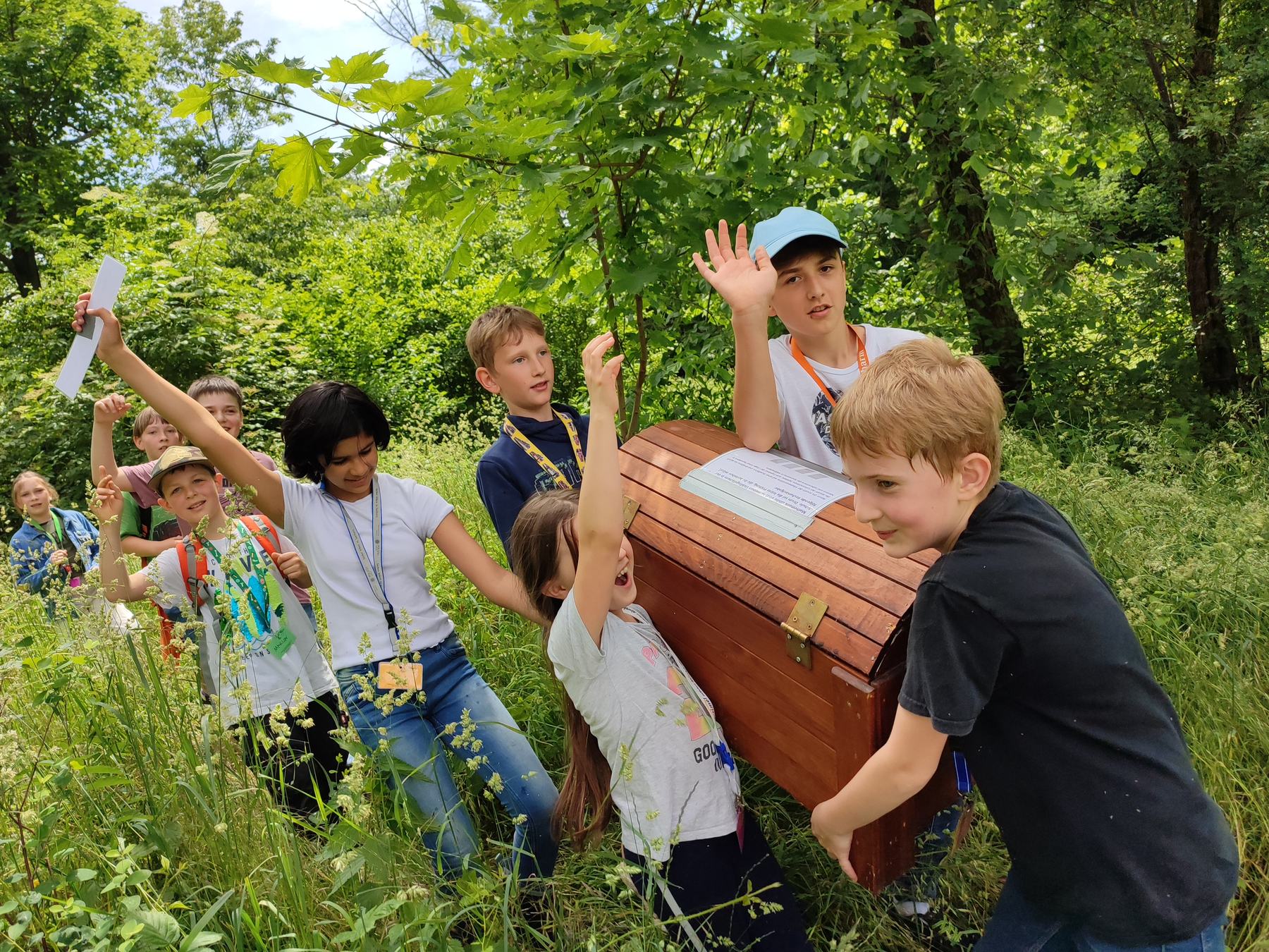 Gruppe von Kindern trägt begeistert eine Schatztruhe