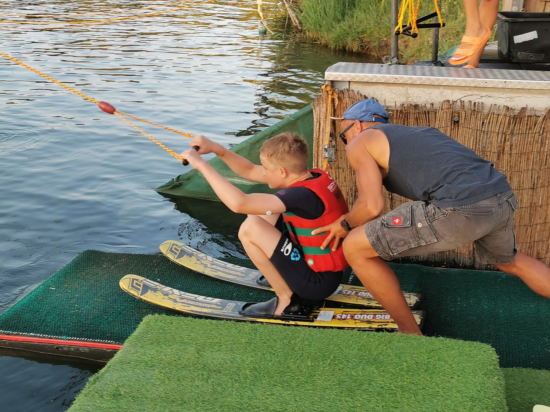Kind mit Wasserskiern auf Startrampe