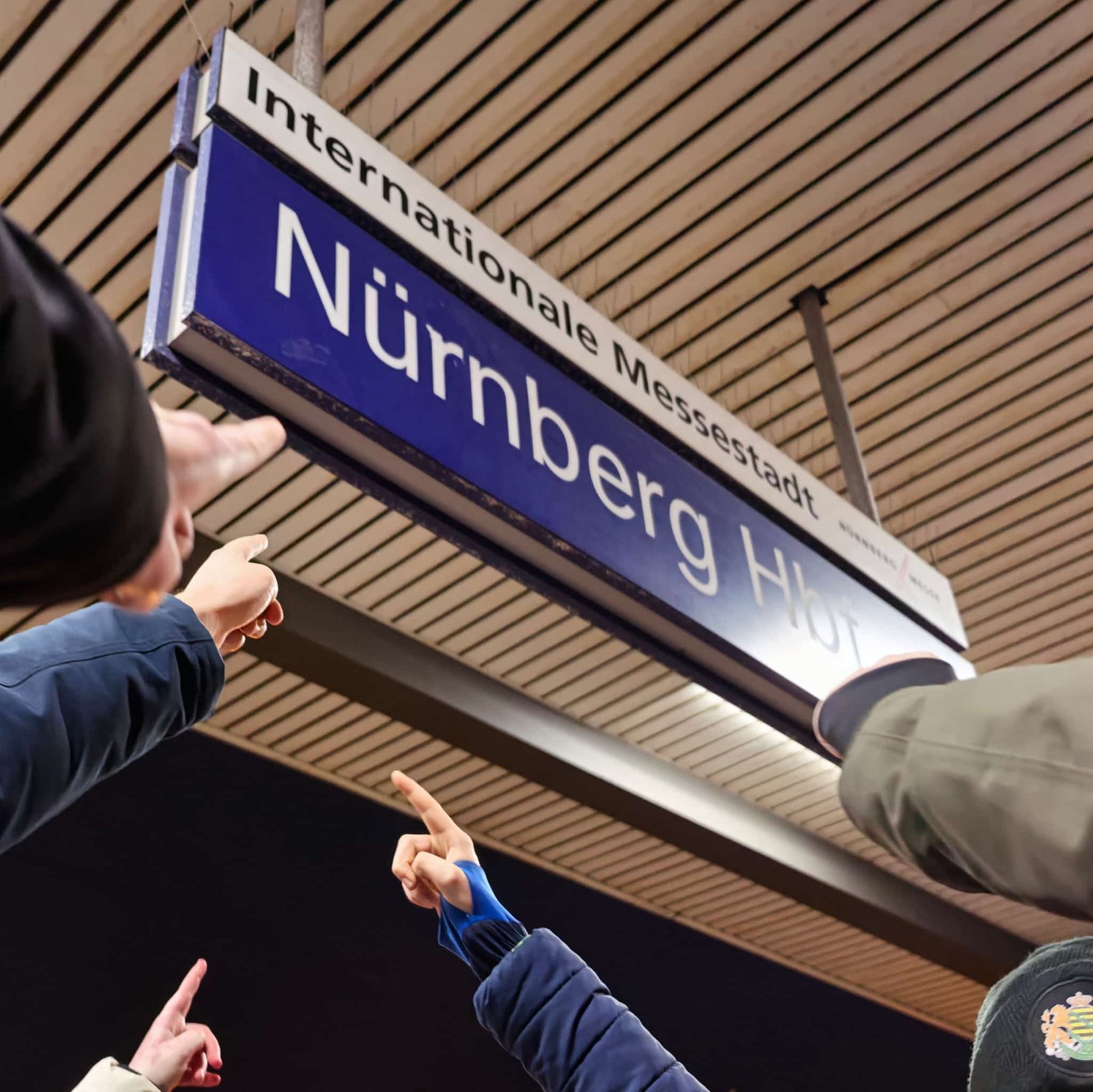 Finger zeigen auf Bahnhofsschild Nürnberg Hbf