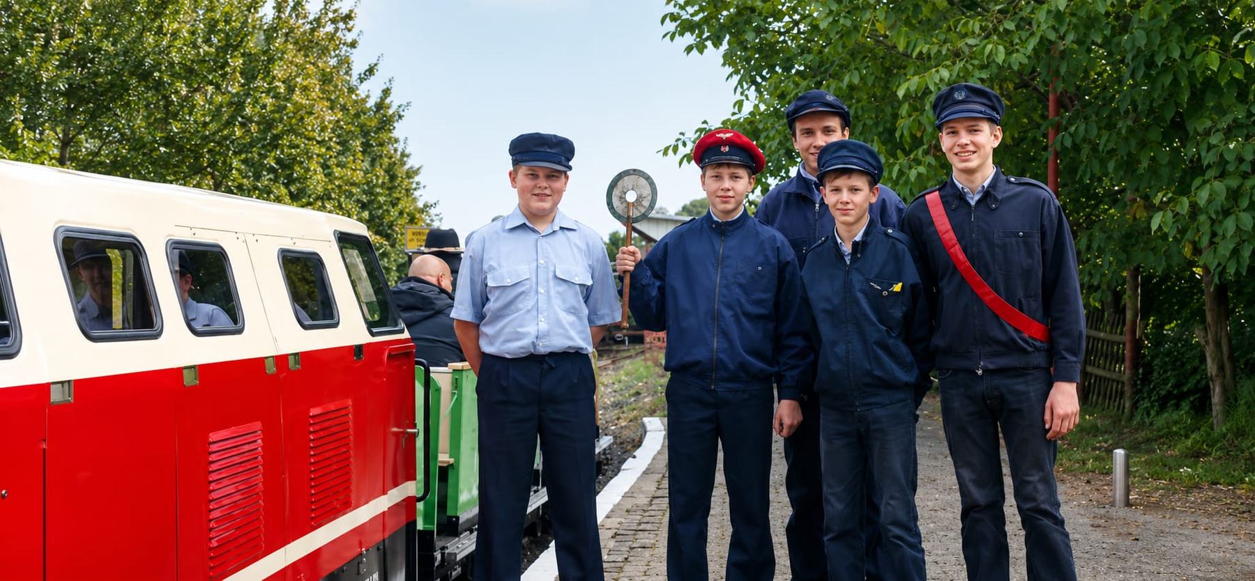 Gruppenbild der Dresdner Parkeisenbahner in Uniform neben dem Zug der Vatteröder Parkeisenbahn. Die Aufsicht hebt den Befehlsstab.